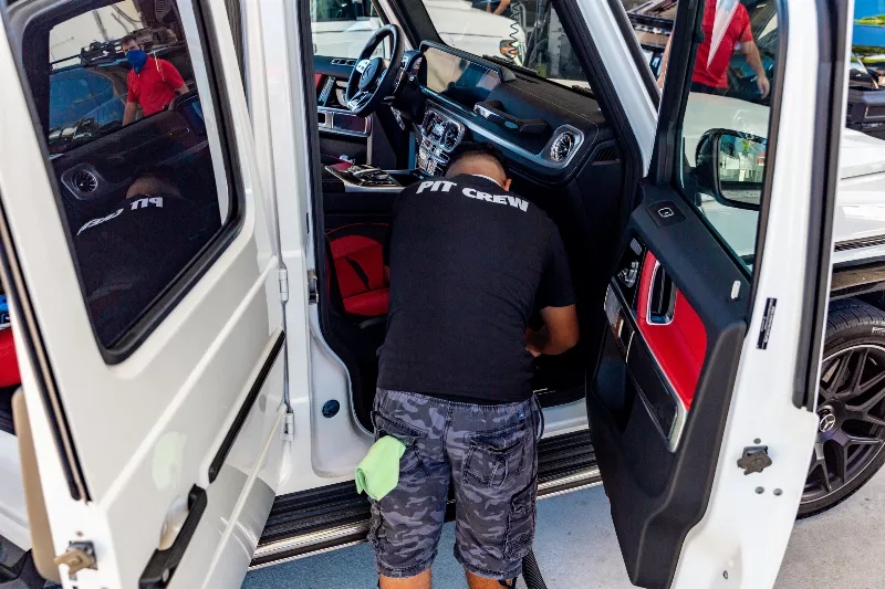 Vacuuming the interior of a car during detailing service at Prestige Auto Spa in Miami.