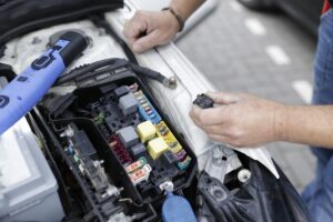 Car mechanic working on automotive electronics and wiring