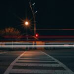Car light streaks across a road at night