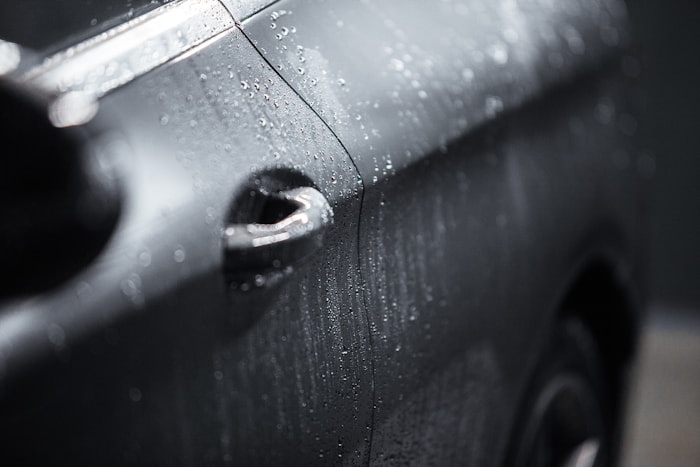 Close up of black car paint surface with rain drops