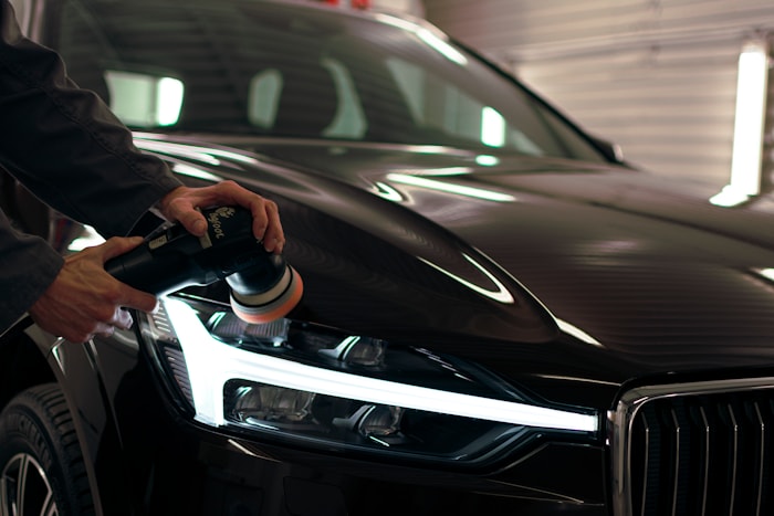 Man using polishing machine for paint correction on car