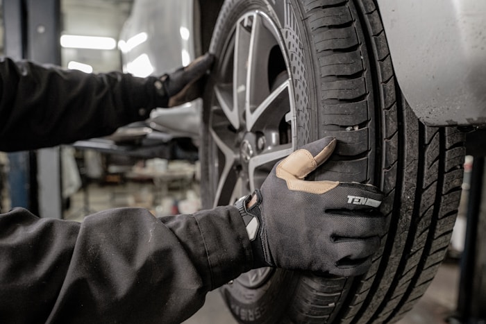 Mechanic changing car tire wearing protective gloves