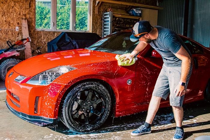 Professional washing a red sports car in a detailing garage